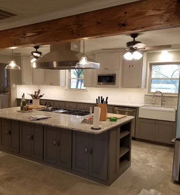 Wide shot of the renovated Cash, Texas kitchen showcasing the center island, structural beam, and cabinetry